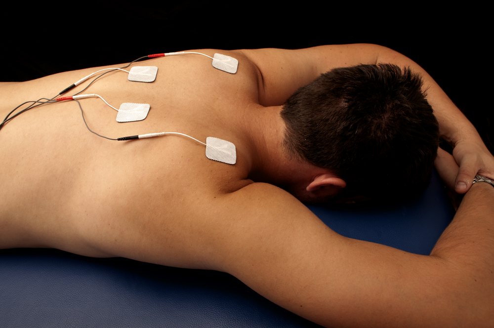 Man laying on his stomach and having Cutera truFlex muscle stimulation done on his back.
