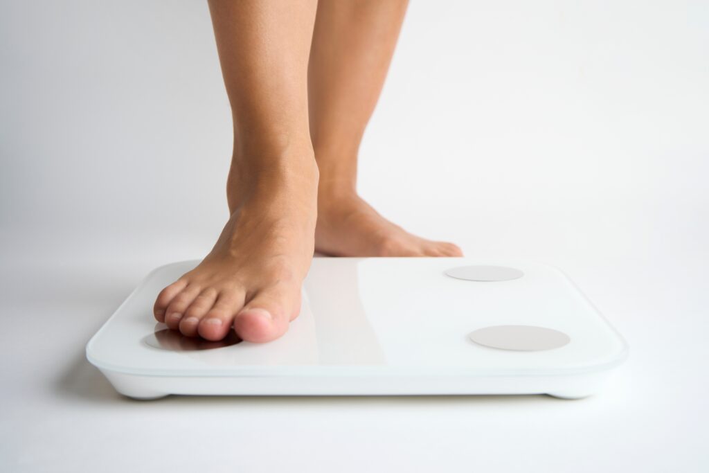 Close up of a woman stepping onto a home scale to weigh in after yet another fad diet