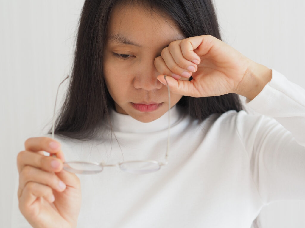 Tired woman rubbing her eyes and suffering from chronic fatigue, in need of treatment